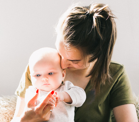 A woman holding a baby under sunlight